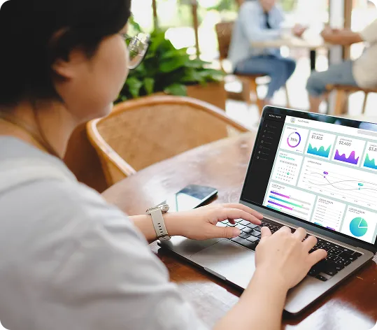 A business owner uses OrderEazi's powerful analytics dashboard on their laptop in a cosy café.