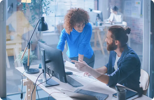 Two team members collaborate enthusiastically over a computer, showcasing how our platform fosters teamwork and efficiency.