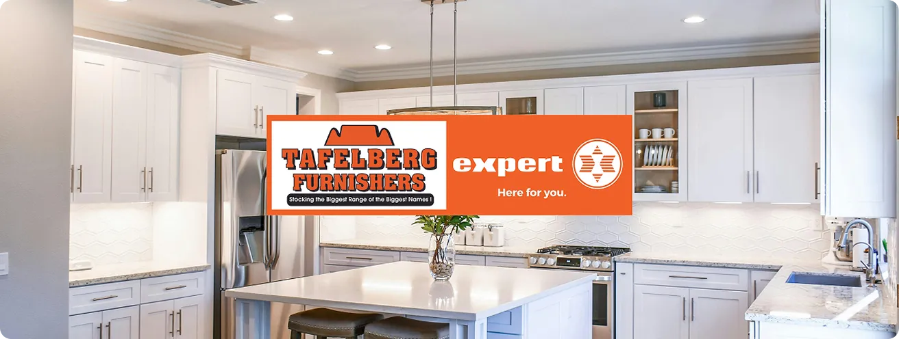 A modern, bright kitchen with white cabinetry and stainless steel appliances showcases Tafelberg Furnishers and Expert's branding. 